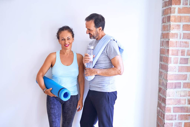Middle age beautiful sporty couple smiling happy. Standing with smile on face looking at camera at gym - Foto, imagen
