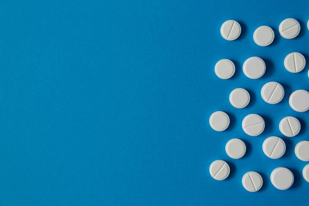 medicína a zdraví, bílé pilulky na modrém pozadí shora - Fotografie, Obrázek