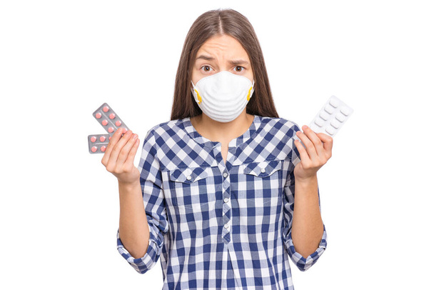 Concept of coronavirus quarantine. COVID-19 - home self isolation. Child wearing medical protective face mask to health protection from influenza virus, isolated on white. Teen girl holds pills. - Фото, изображение