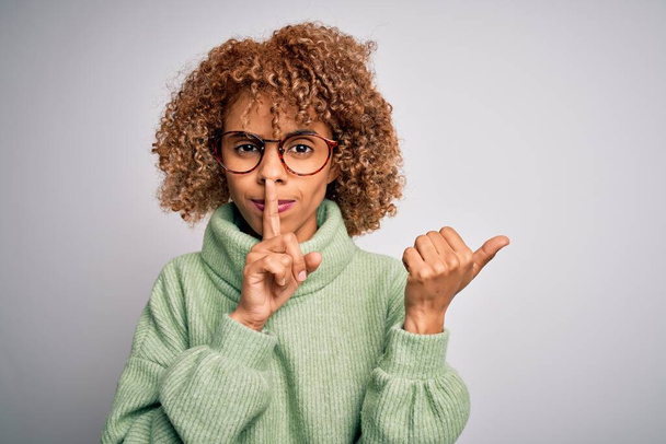 Якась вродлива афро-американська жінка у світильнику і окулярах просить мовчати, поклавши палець на губи, що спрямовані з рукою на бік. Тиша і таємна концепція. - Фото, зображення