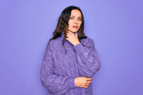 Young beautiful woman wearing casual turtleneck sweater standing over purple background Touching painful neck, sore throat for flu, clod and infection - Fotoğraf, Görsel