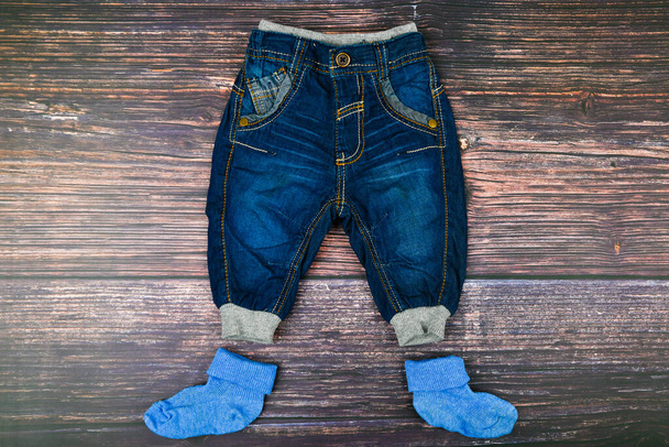 Dětské džíny na dřevěném pozadí. Módní koncept. Koncept oblečení. Tmavé dřevěné pozadí. Chlapeček a džíny. Dětské oblečení - Fotografie, Obrázek