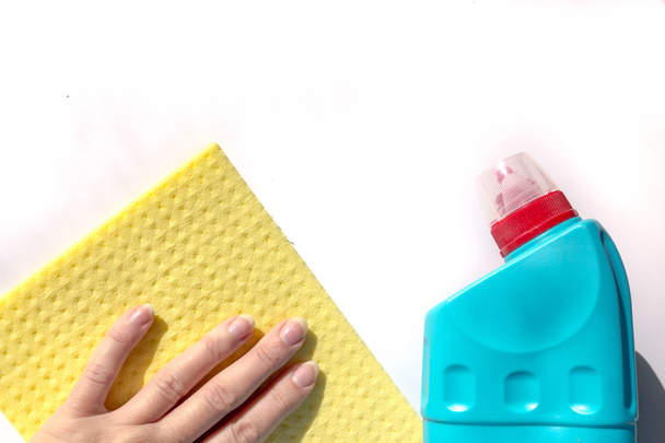 家の掃除や消毒,コロナウイルスの予防.塩素を含まない消毒剤の青いボトルとセルロース洗浄布で白い表面を拭く女性の手コピースペースを水平方向に閉じる - 写真・画像