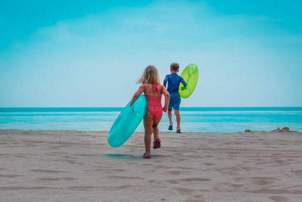 szczęśliwy chłopiec i dziewczyna z platformami biegać pływać na plaży - Zdjęcie, obraz