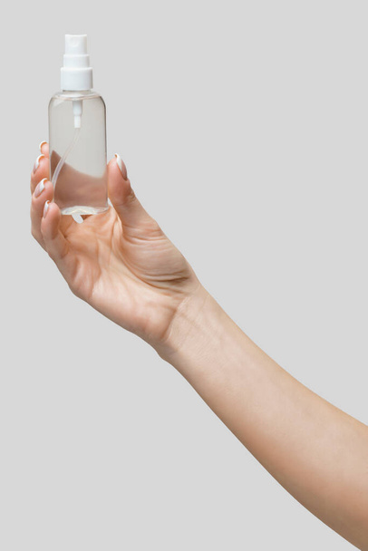 Female hands using hand sanitizer spray dispenser over light grey background - Foto, Bild