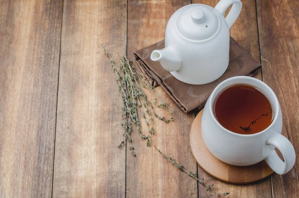 Thyme herbal tea in a white cup and kettle on a wooden table, space for a text - Foto, Imagem