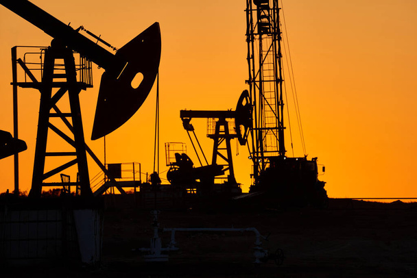 Ölpumpe Ölplattform Energie industrielle Maschine für Erdöl in den Sonnenuntergang Hintergrund für Design. Ölindustrie weltweit. Westliche Region Kasachstans. - Foto, Bild