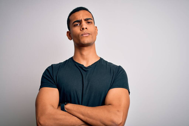 Young handsome african american man wearing casual t-shirt standing over white background skeptic and nervous, disapproving expression on face with crossed arms. Negative person. - Photo, Image