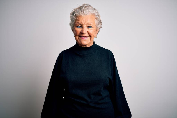 Senior beautiful woman wearing casual black sweater standing over isolated white background with a happy and cool smile on face. Lucky person. - 写真・画像