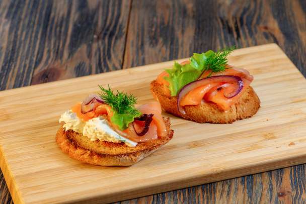 Fish and greens sandwich on a wooden cutting board - Фото, изображение
