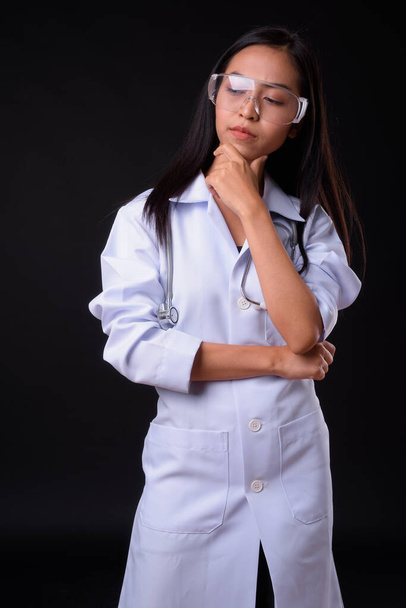Portrait of young Asian woman doctor as scientist thinking - Fotó, kép