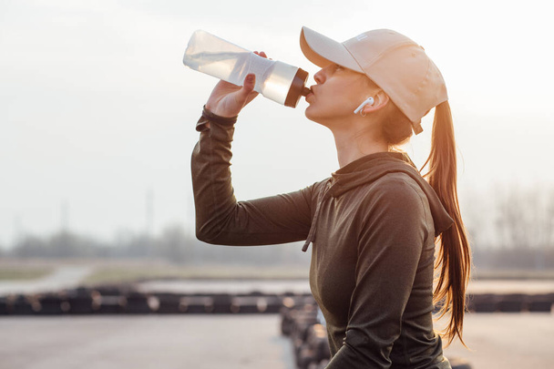 mooi meisje in de ochtend training drinkt water uit een fles - Foto, afbeelding