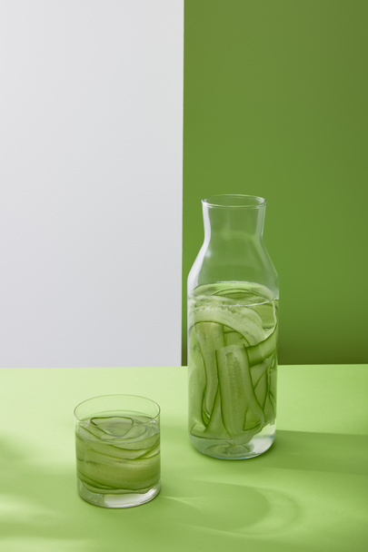nagy látószögű kilátás palack és üveg ital szeletelt uborka szürke és zöld háttér - Fotó, kép