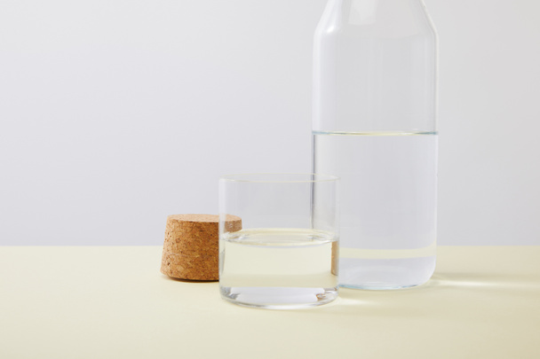 Close up view of bottle, cork and glass filled with water isolated on grey - Фото, изображение
