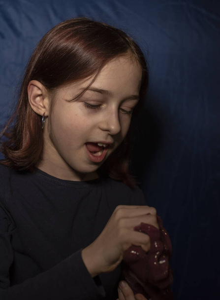 Girl with a slime. Little girl making homemade toy. Child having fun making purple slime. Kid playing with slime. Relax and Satisfaction. Oddly satisfying red slime for pure fun and stress relief. - Photo, Image