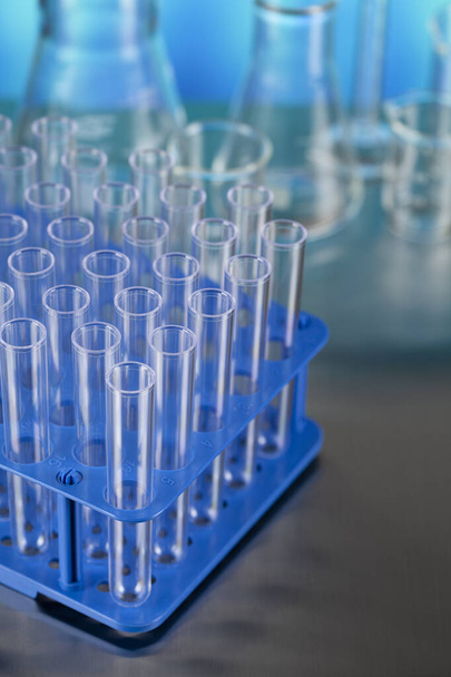 Laboratóriumi kémcsövek, mint a fémasztalon és a kék háttéren végzett orvosi vizsgálatok szimbóluma - Fotó, kép