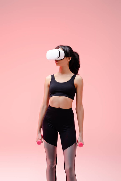 african american woman in sportswear and virtual reality headset exercising with dumbbells on pink   - Photo, Image
