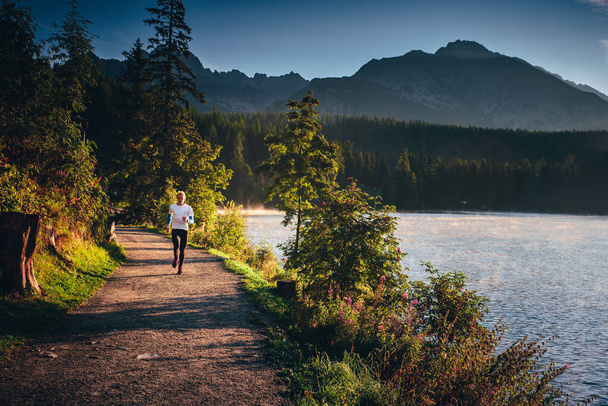 Morning free run in trail by mountains and lake, Strbske pleso, Slovakia - Photo, Image