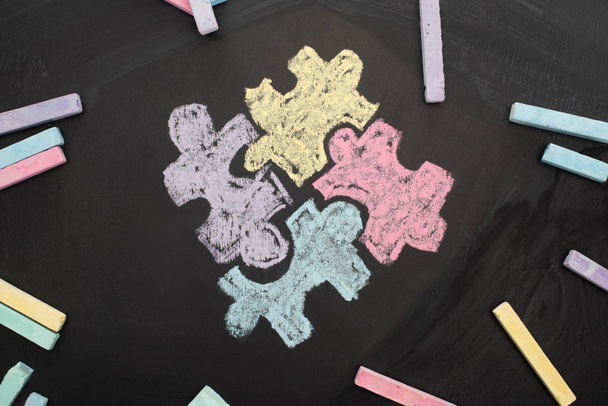vista superior de tiza en pizarra con dibujo de rompecabezas para el Día Mundial de la Concienciación sobre el Autismo
 - Foto, imagen