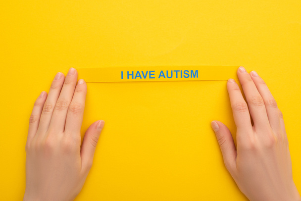 vista parcial de la mujer que sostiene el brazalete con tengo inscripción de autismo en amarillo
 - Foto, Imagen