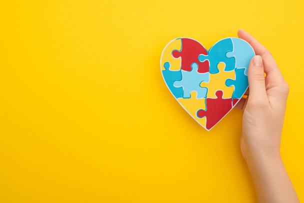 cropped view of woman holding puzzle heart on yellow   - Photo, Image
