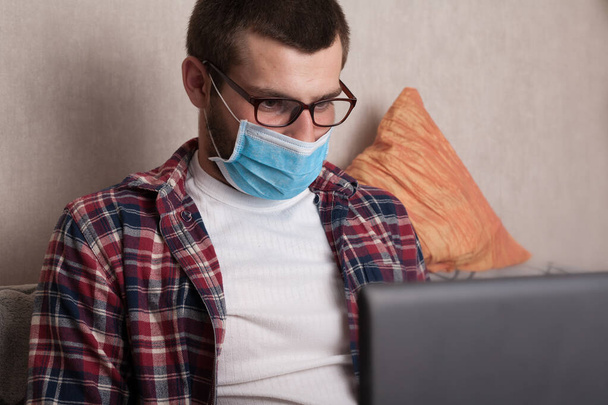 Quarantine, guy working at home with a laptop with a cup of coffee. Work at home with coronavirus and protect the health of workers. - Foto, immagini