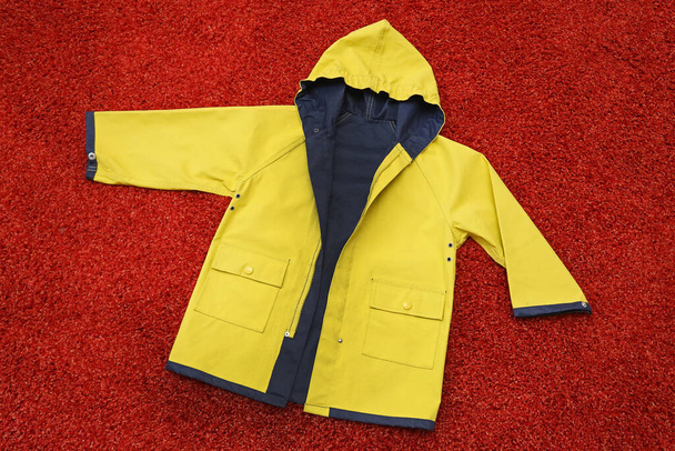 żółty płaszcz przeciwdeszczowy na czerwonej podłodze - Zdjęcie, obraz