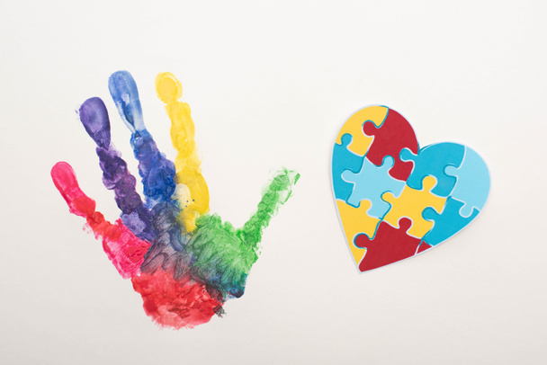 górny widok kolorowych odcisków dłoni i serca puzzle na białym na Światowy Dzień Świadomości Autyzmu - Zdjęcie, obraz