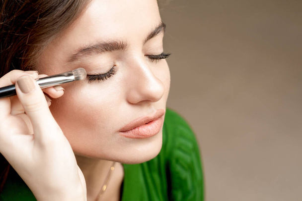 Woman applying eyeshadow powder, eye makeup close up with copy space. - Photo, Image