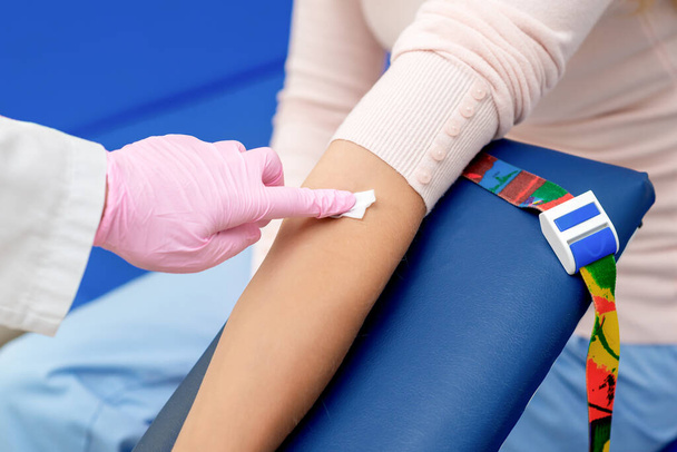 医療センターで注射ワクチンを与える前に綿で腕の皮膚を消毒看護師. - 写真・画像