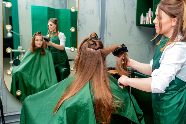 Hairdresser making hairstyle for client at the beauty salon. - Photo, Image
