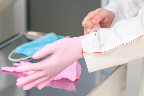 病院でピンクのラテックス手袋を着るを閉じる. - 写真・画像