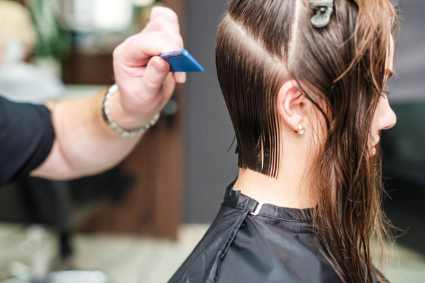 Coiffeur peigner les cheveux féminins avec un peigne dans le salon de coiffure
. - Photo, image