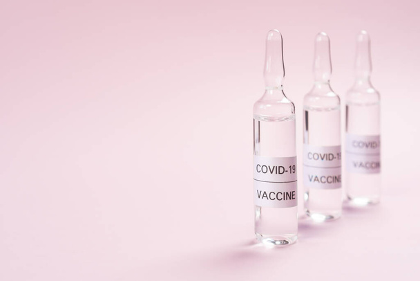 Vakcina a COVID-19-hez. Rózsaszín hátterű ampullák a koronavírus elleni gyógyszerrel. Másolótér. Közelkép. Gyógymód kifejlesztése és használata egy új vírusra - Fotó, kép