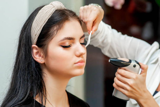 Maquillaje artista pulverizaciones de mano con ayuda aerógrafo en la cara de la mujer maquillaje de fijación
. - Foto, Imagen