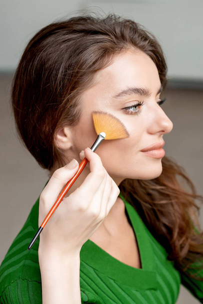 Make-up kunstenaar droge cosmetische tonale foundation op het gezicht met behulp van make-up borstel, schoonheid met perfecte natuurlijke make-up aanbrengen blusher. - Foto, afbeelding