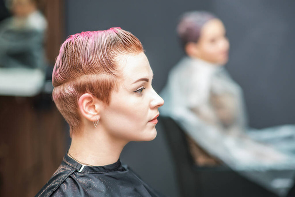 Atraktivní žena s půvabem mokré krátké růžové vlasy v salonu krásy. Boční pohled. - Fotografie, Obrázek