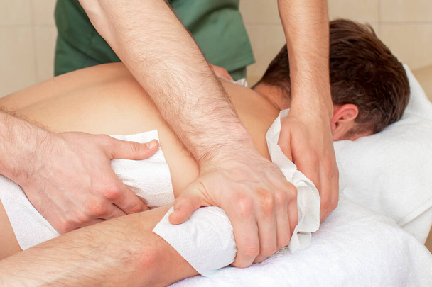 Gros plan massage des mains et des épaules sur le dos de l'homme
. - Photo, image