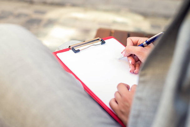 Primer plano de una mano femenina escribiendo en un planificador en blanco con un bolígrafo. Concepto educativo. Copiar espacio, maqueta
. - Foto, imagen