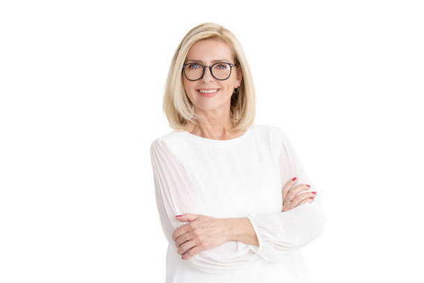 Portrait shot of smiling blonde senior woman standing with arms crossed at isolated white background. - Φωτογραφία, εικόνα
