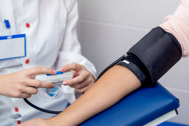 Лікар перевіряє кров'яний тиск на руку молодої жінки крупним планом
. - Фото, зображення
