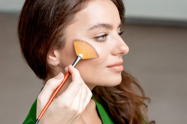 Makeup artist working with brush on model face with copy space. - Photo, Image