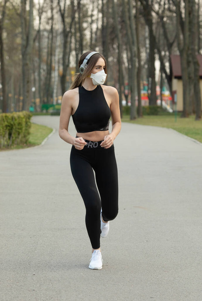 Retrato de mulher esportiva caucasiana vestindo uma máscara de proteção médica enquanto corre no parque. Vírus Corona ou Covid-19, está se espalhando por todo o mundo
. - Foto, Imagem