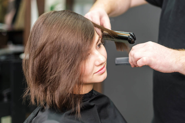 Професійний перукар випрямлення коричневого волосся з випрямленням волосся в салоні краси
 - Фото, зображення