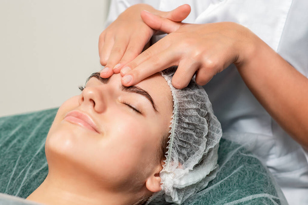 Beautiful young woman receiving face massage, close up. - Фото, изображение