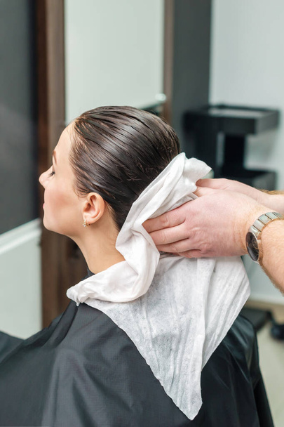 Professionele kapper vegen haar van haar klant na het wassen in schoonheidssalon - Foto, afbeelding