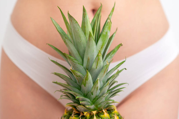 Ananasblätter auf weißem Höschen Hintergrund des Frauenkörpers, Epilation oder Enthaarungskonzept oder Intimhygiene. - Foto, Bild