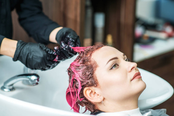 Friseur wäscht gefärbte Haare in rosa von Frau im Waschbecken, Nahaufnahme. - Foto, Bild