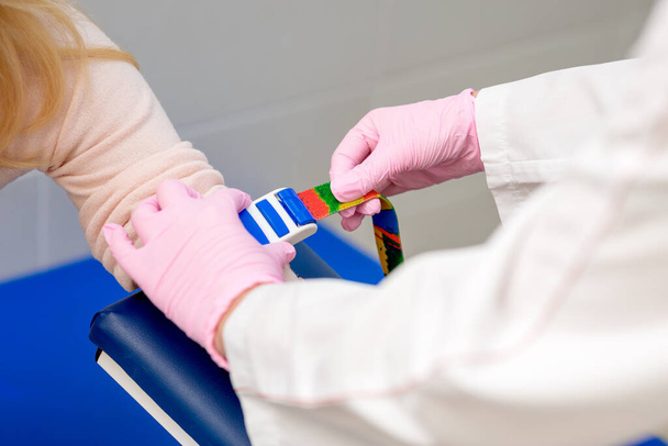 Nurse tightens the harness on the arm to take blood from a vein for analysis. - Foto, afbeelding