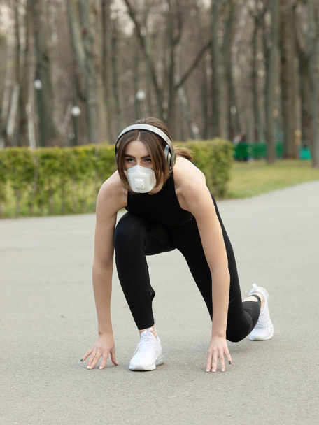 Portret van een blanke sportieve vrouw met een medisch beschermend gezichtsmasker tijdens het rennen in het park. Corona virus of Covid-19, verspreidt zich over de hele wereld. - Foto, afbeelding